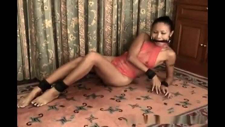 Стройная азиатская девушка в красном нижнем белье, в наручниках и с кляпом во рту.