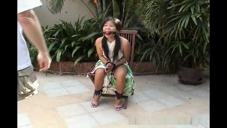 Привлекательная азиатская девушка привязана к стулу.